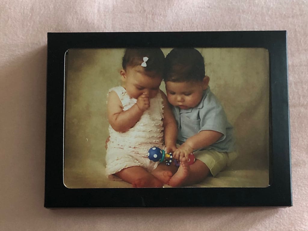 A photo of a baby boy and girl inside a black box with a frame lid