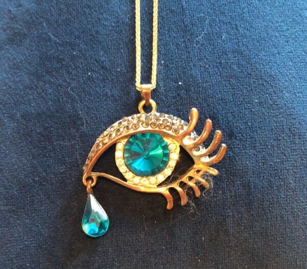 Gold eye with teardrop necklace on a dark blue cloth (600 x 526)
